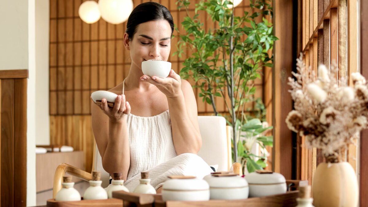 A young woman enjoys the aroma of essential oils in a tropical setting. Aromatherapy, spa and relaxation concept.