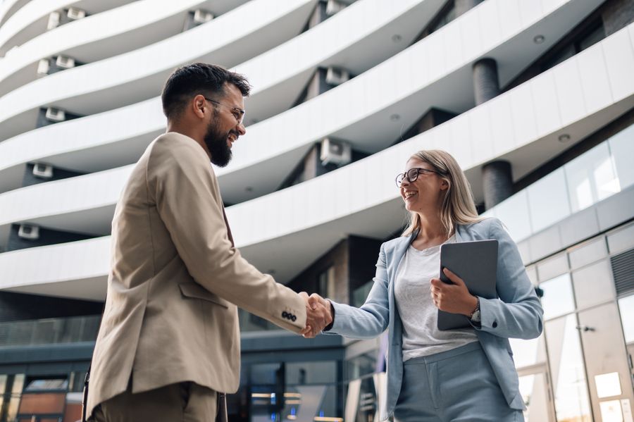 Business people shaking hands in front of modern office building