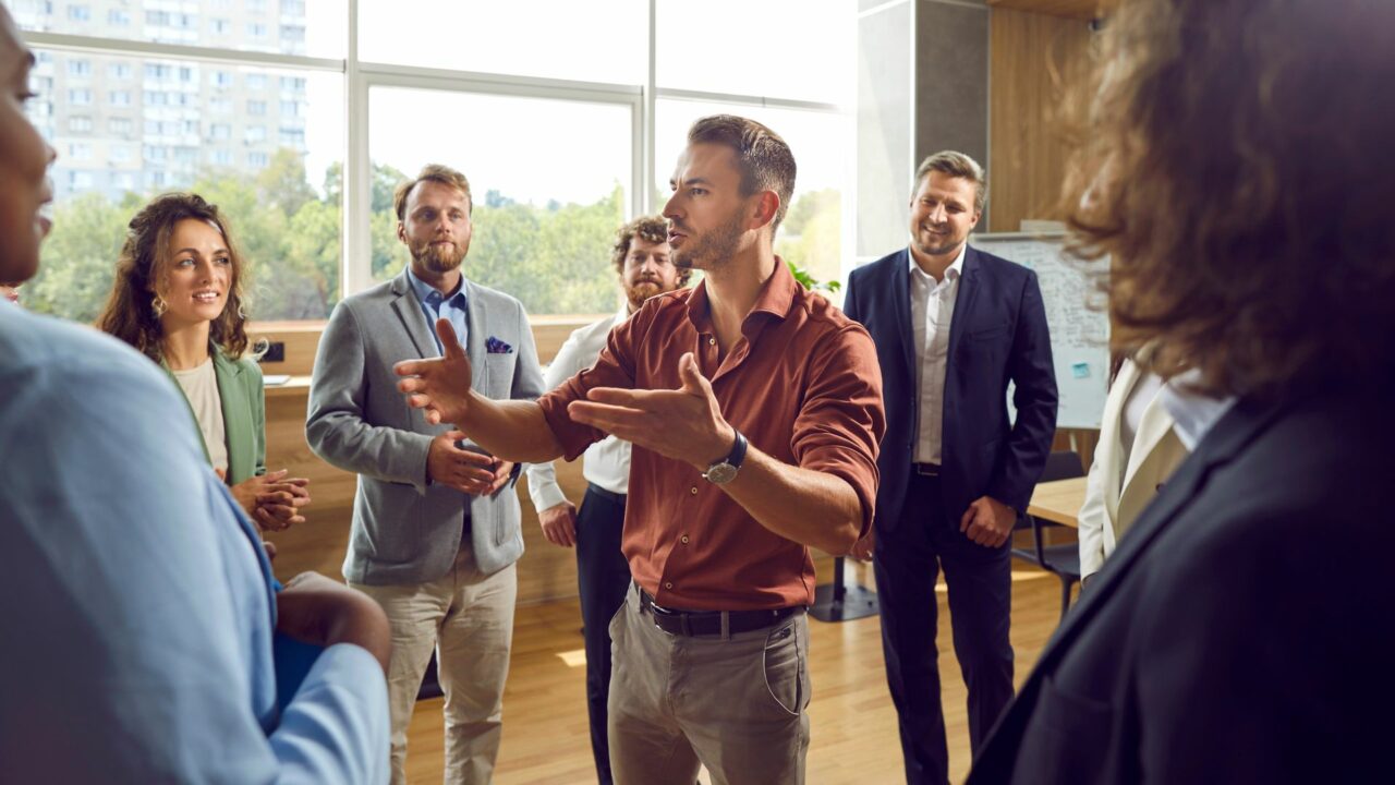 Male business trainer or psychologist talking about teamwork with a group of people