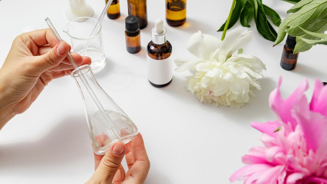 Woman holding lab flask during experimenting of production of peony oils, perfume and cosmetics